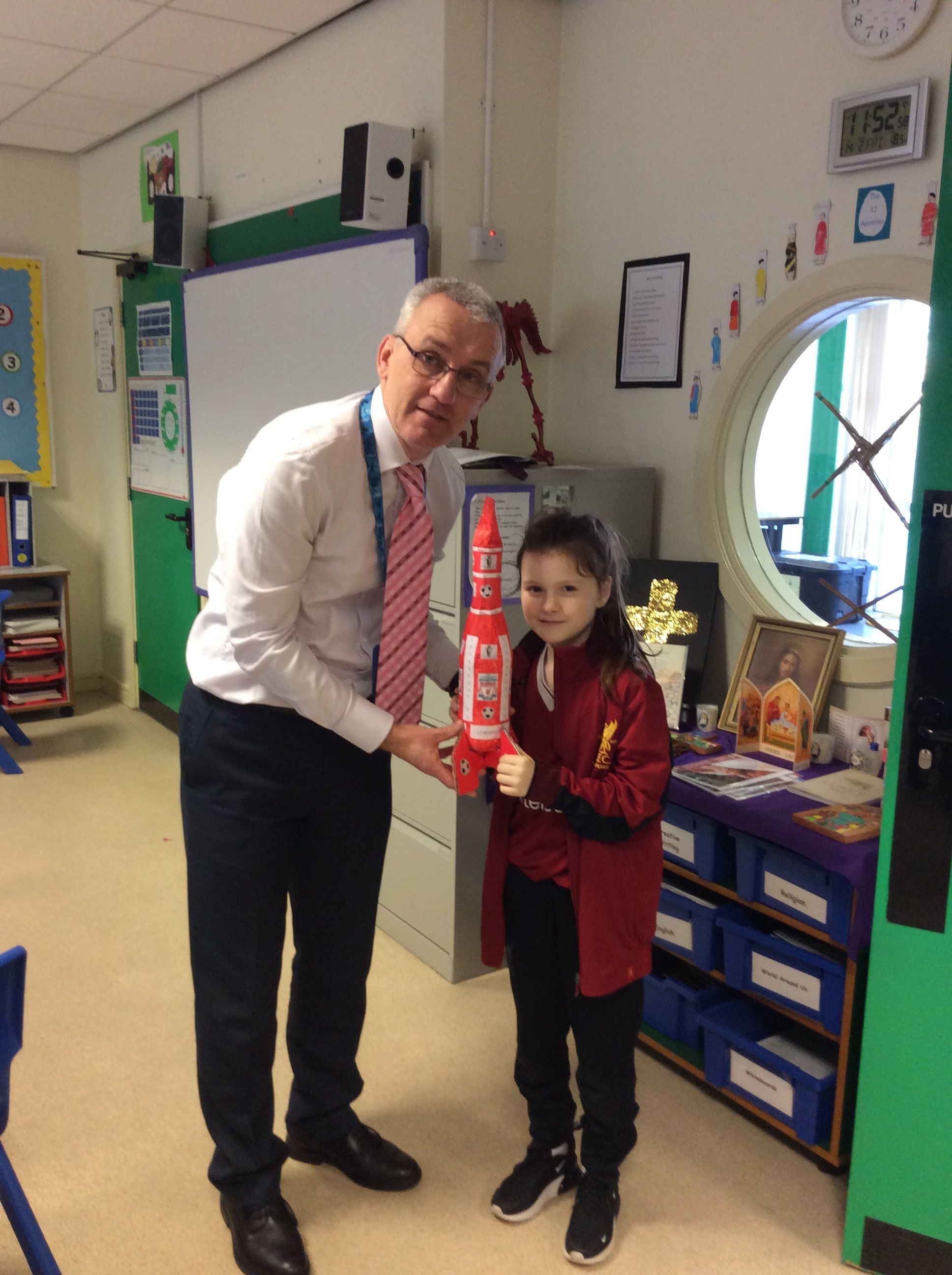 Ava presenting Mr. Carlin with a Liverpool Rocket "because Liverpool are flying at the minute".